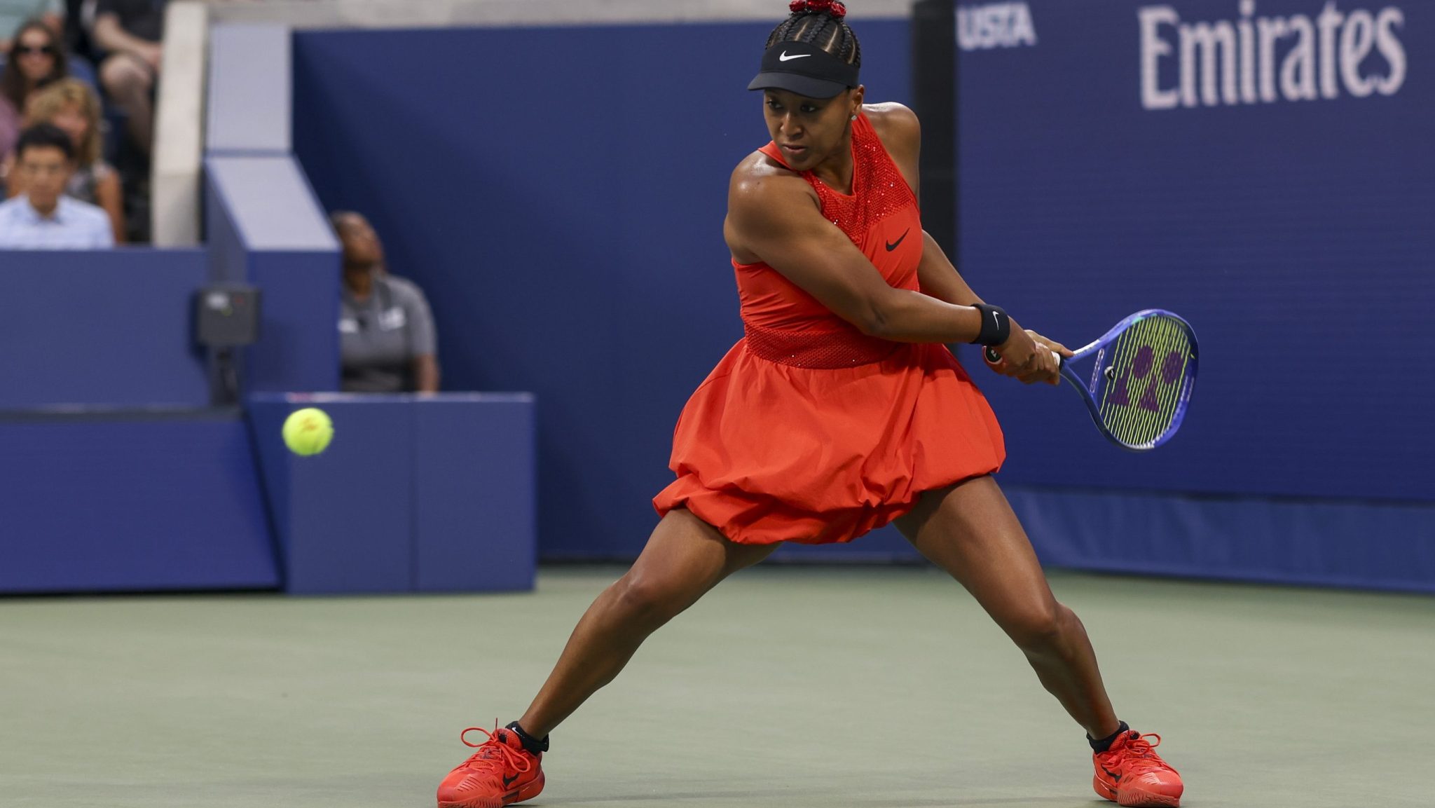 Naomi Osaka playing tennis in a red outfit