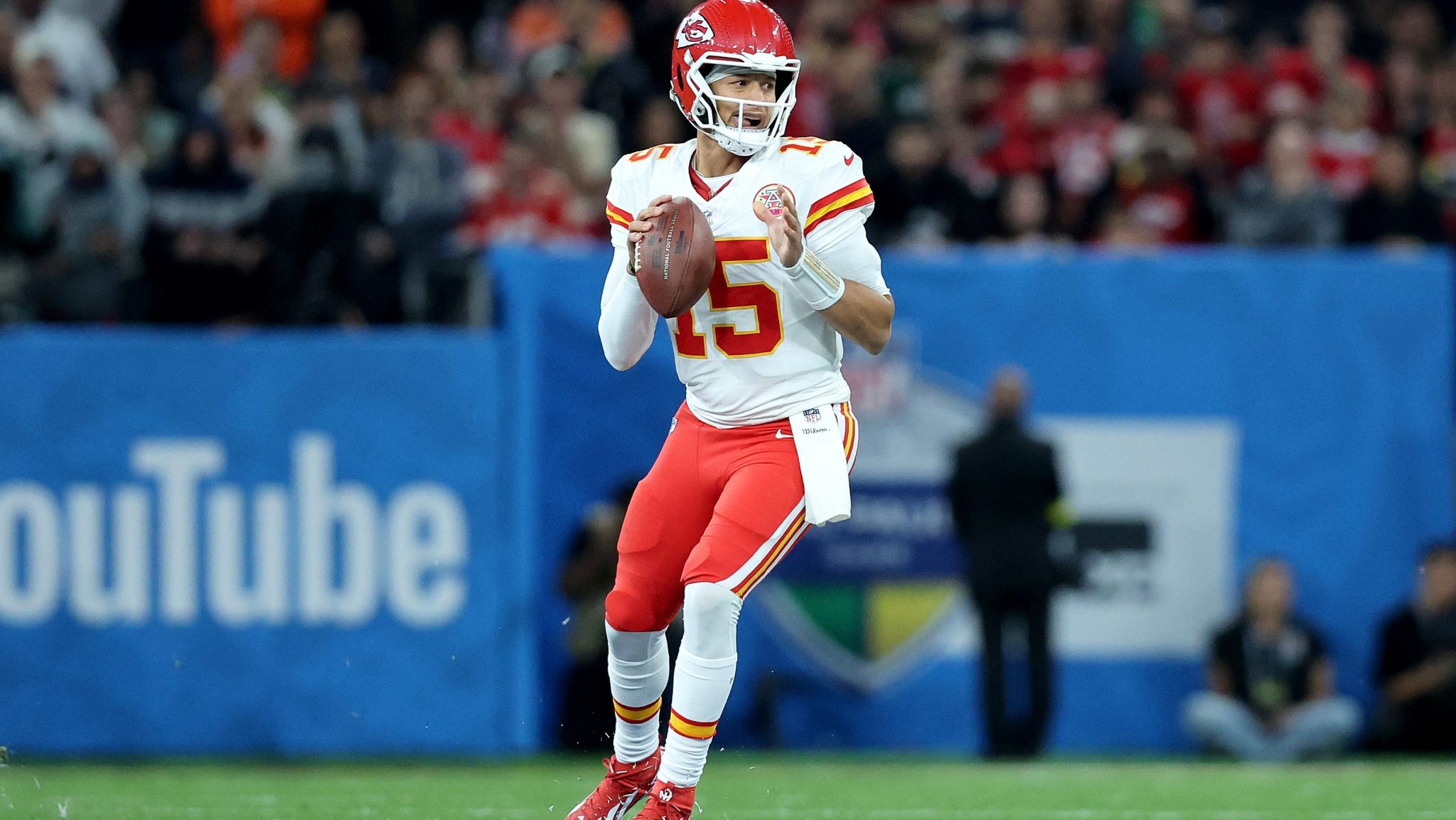 Patrick Mahomes holds the football and looks down the field.