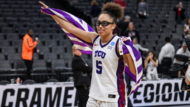 Olivia Miles smiles while holding the TCU flag.