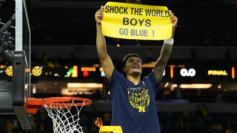 Yaxel Lendeborg holds up a sign and celebrates while cutting down the nets.