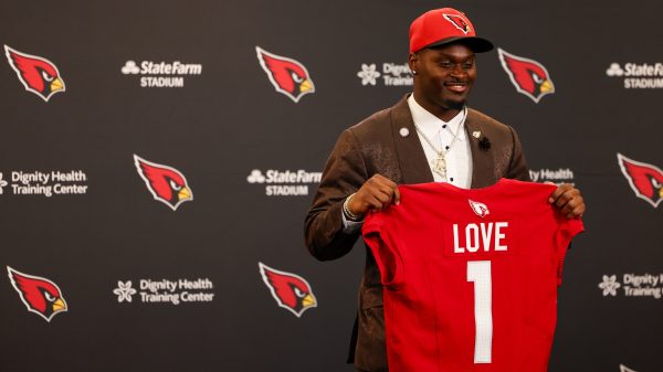 Jeremiyah Love poses with his Arizona Cardinals jersey