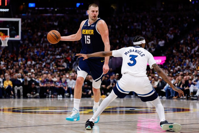 Nikola Jokic handles the ball while a defender guards him.