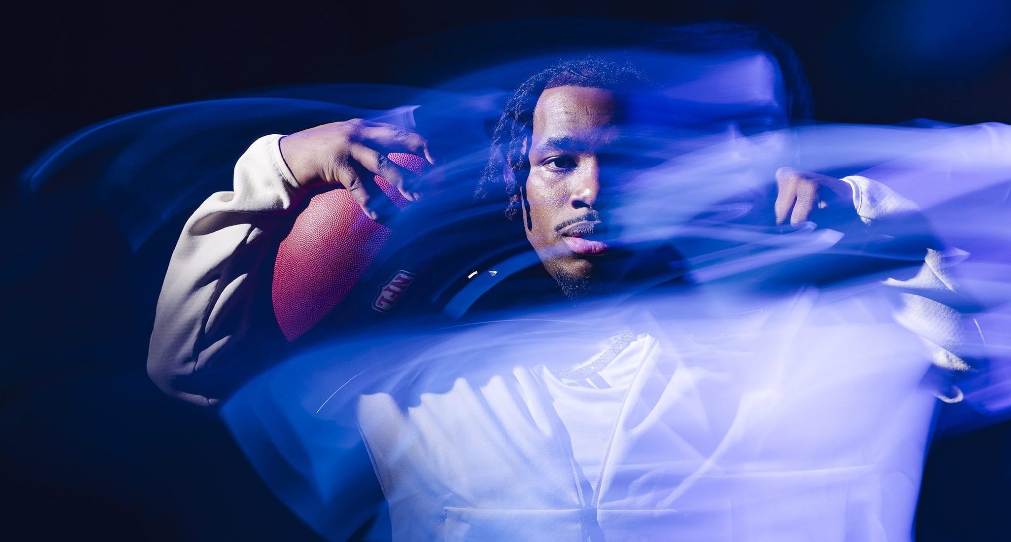 Jonah Coleman flexes with football with blue light streaks around him.