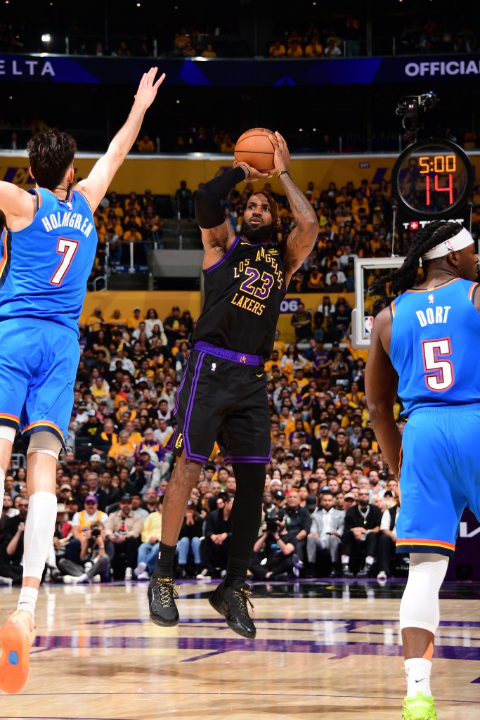LeBron James shoots the ball as a defender puts his arm up.