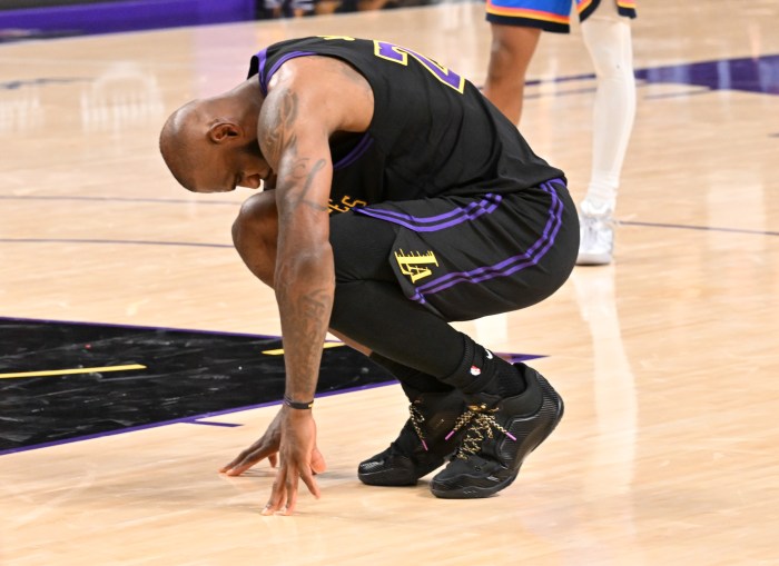 LeBron James bends down and touches his hands on the court