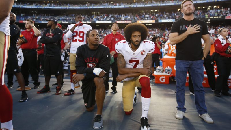 Eric Reid and Colin Kaepernick kneel on the sideline during the national anthem