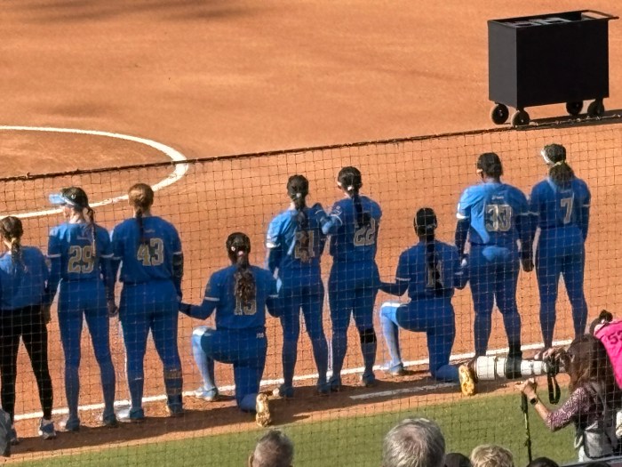 UCLA players Jordan Woolery (fourth from left) and Soo-Jin Berry (third from right) kneel during the national anthem before the team's game against Alabama on Thursday at the Women's College World Series in Oklahoma City.