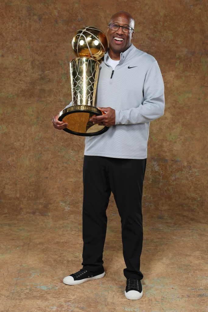 Mike Brown smiles as he poses for a photo with the NBA championship trophy