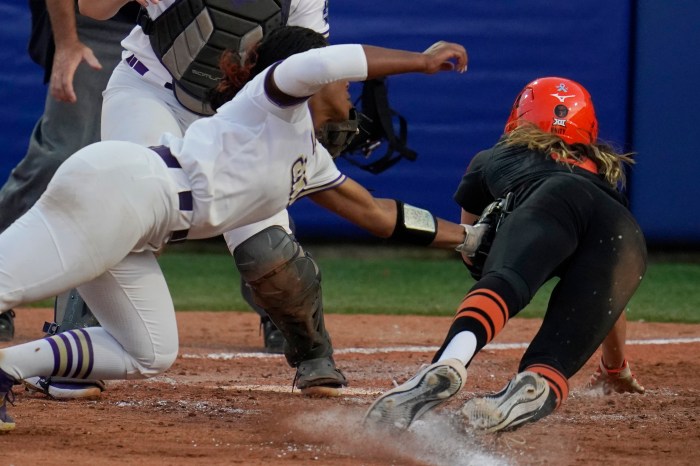 James Madison pitcher Odicci Alexander (left) tags out Oklahoma State's Scotland David (right) at home plate in the seventh inning of a Women's College World Series game on June 4, 2021, in Oklahoma City. 