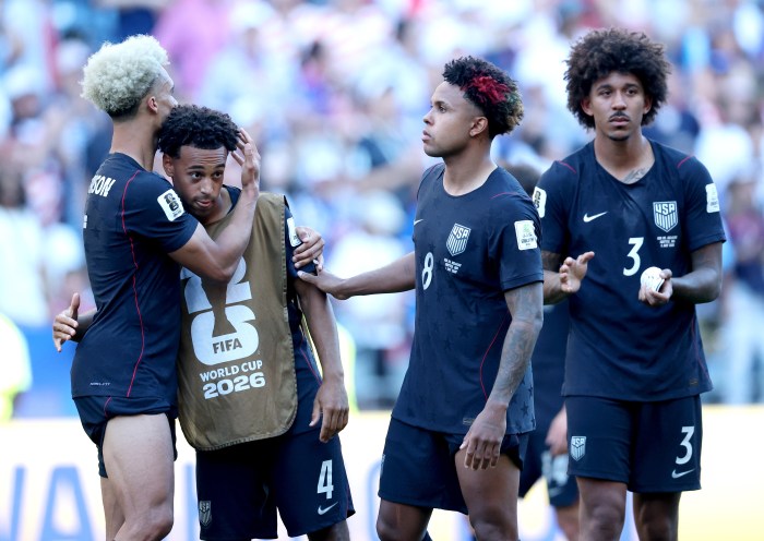 Tyler Adams is surrounded by teammates and gets a hug after losing in the World Cup.