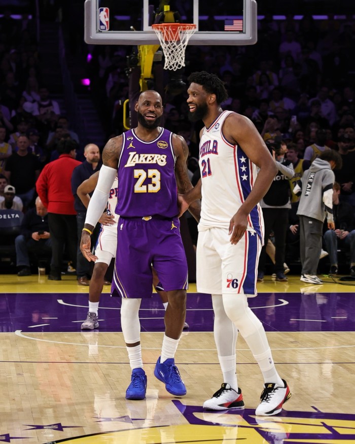 Joel Embiid and LeBron James smile as they talk on the court.