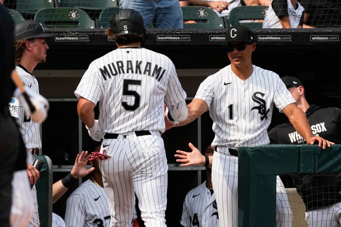 Munetaka Murakami is congratulated by manager Will Venable in the dugout.