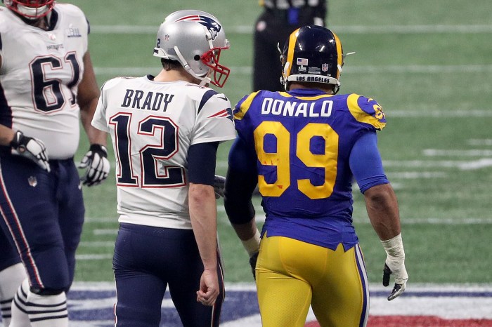 Tom Brady and Aaron Donald with their backs to the camera talking to each other on the field.