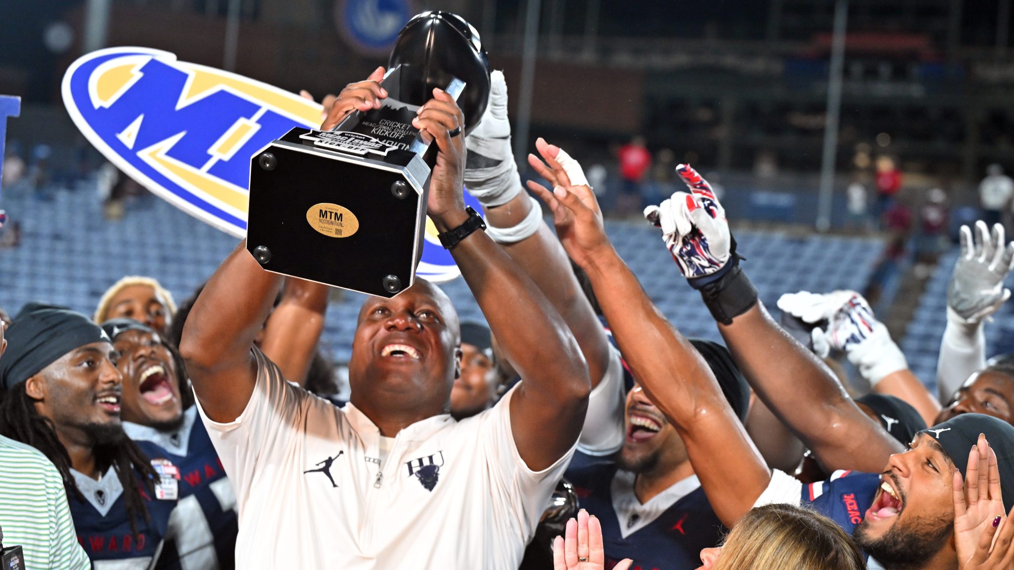 Howard head football coach Ted White (center) hoists the trophy after his team's 31-24 win over Alabama A&M on Saturday at the 2026 Cricket MEAC/SWAC Challenge Kickoff at Center Parc Stadium in Atlanta.