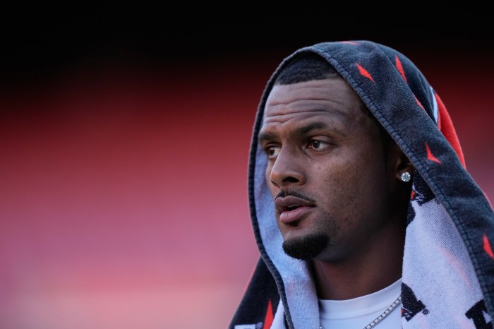 Deshaun Watson watches from the sidelines with a towel on his head.