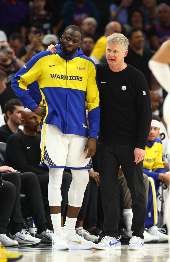 Draymond Green and Steve Kerr watch the game from the sidelines.