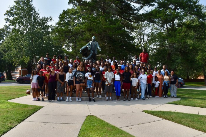 The Tuskegee University men’s and women’s soccer teams pose for a photo in front of the Booker T. Washington "Lifting the Veil of Ignorance" statue on campus. 