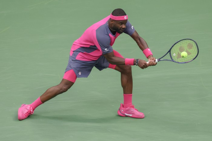 Frances Tiafoe hits the ball with his tennis racket.