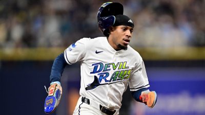 Chandler Simpson dashes around third base as his helmet slowly falls off his head.