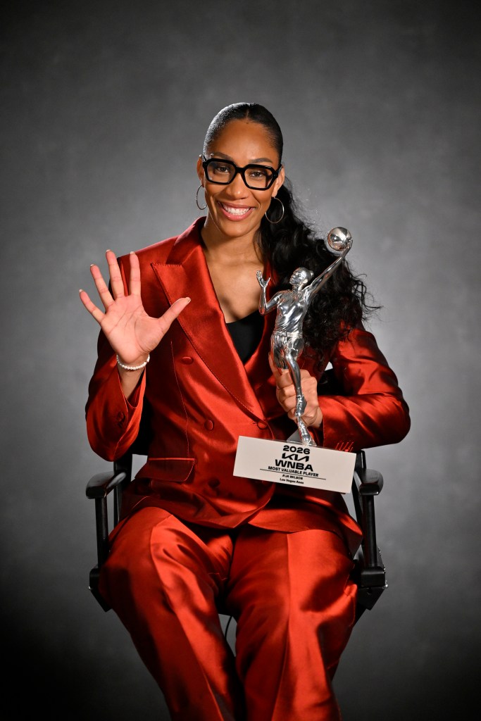 A'ja Wilson puts her right arm up and holds the WNBA MVP award with her left arm.
